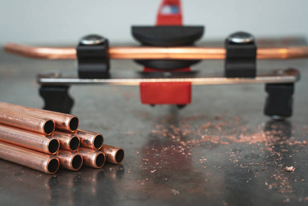 Pipe bender tool and a brass pipes on a workbench of fitter background